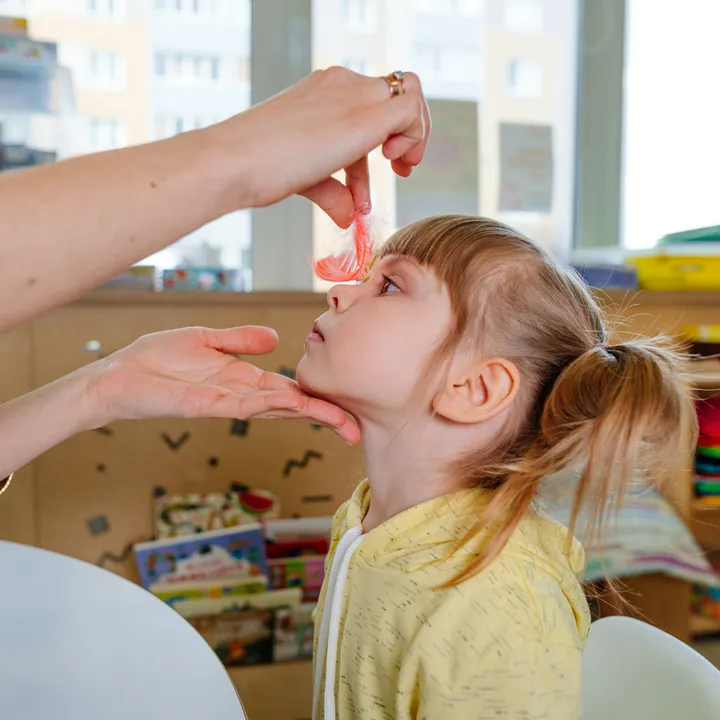 A therapist supporting a child during a learning activity