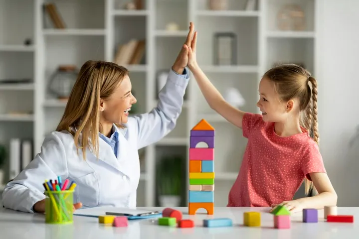 A child celebrating progress with a therapist
